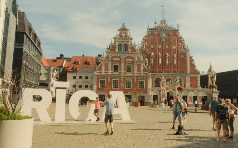 People exploring the vibrant Town Hall Square in Riga with the iconic House of the Blackheads in the background.