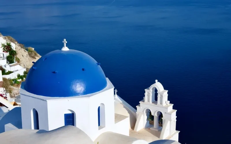 Breathtaking view of Santorini's blue-domed church overlooking the Aegean Sea, capturing Greek architecture.