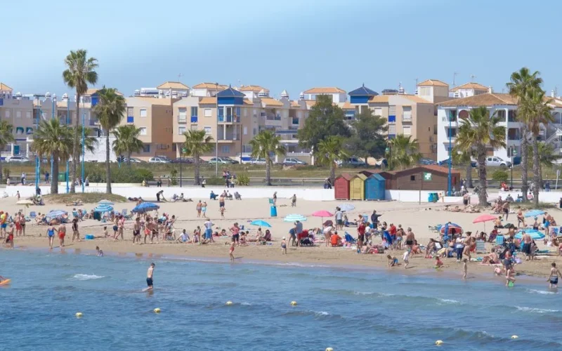 Enjoy a lively summer day at a bustling Mediterranean beach with people enjoying the sunshine.