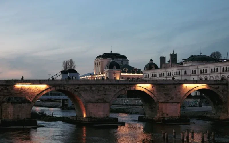Evening shot of Stone Bridge over Vardar River in Skopje, illuminated by lights.