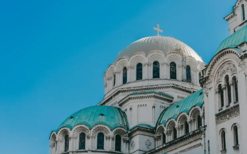 The iconic domes of Alexander Nevsky Cathedral against a clear blue sky in Sofia, Bulgaria.