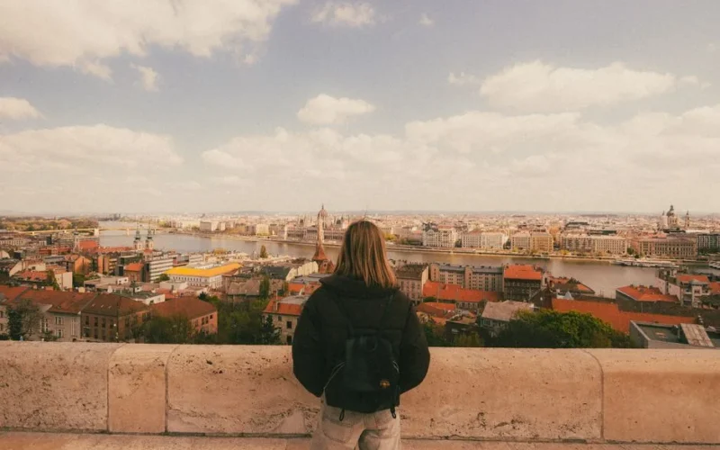 Woman admiring the panoramic view of Budapest from a high vantage point on a sunny day.