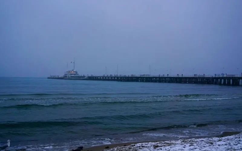 Capture of Sopot Pier with gentle waves under a moody winter twilight sky.