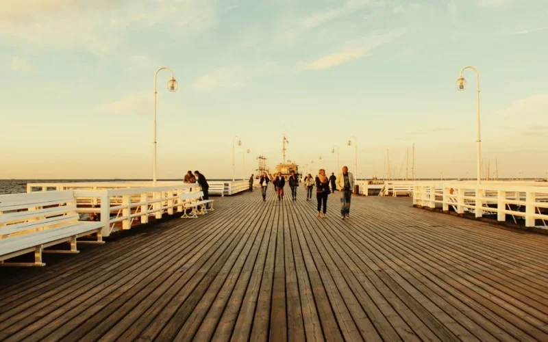 People walking along the Sopot Pier during sunset, capturing a serene seaside moment in Poland.