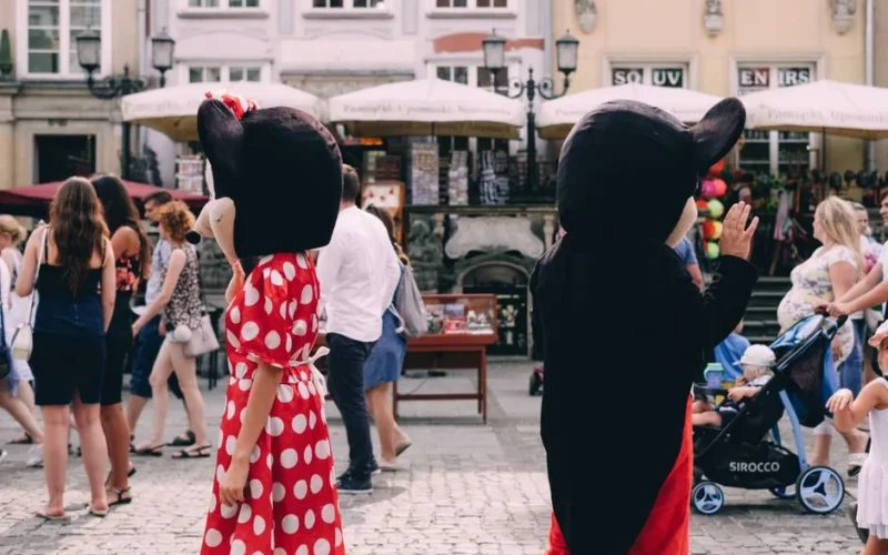 Costumed characters entertain a crowd on a sunny day in a vibrant outdoor setting.