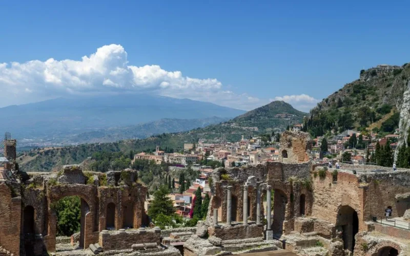 Explore the awe-inspiring ruins of the Ancient Theatre of Taormina, Sicily with Mount Etna in the background.