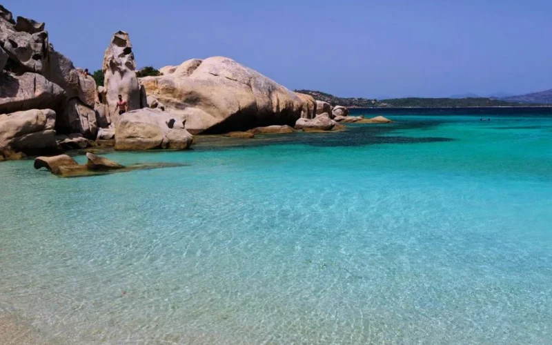 Breathtaking beach with clear turquoise water and unique rock formations under sunny skies.
