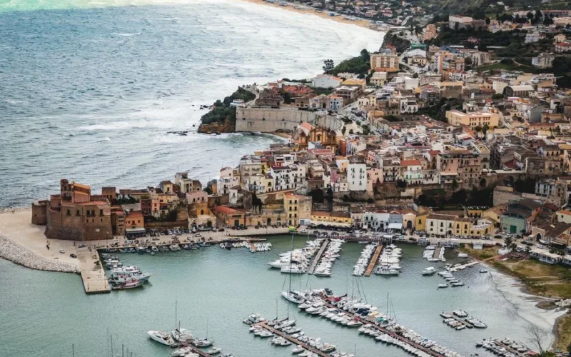 A picturesque aerial shot of a coastal town in Sicily, showcasing the marina and historic architecture.