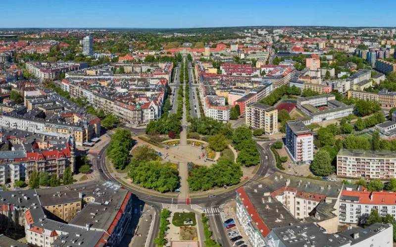 A stunning aerial view of Szczecin, showcasing its urban structure, residential buildings, and greenery on a sunny day.