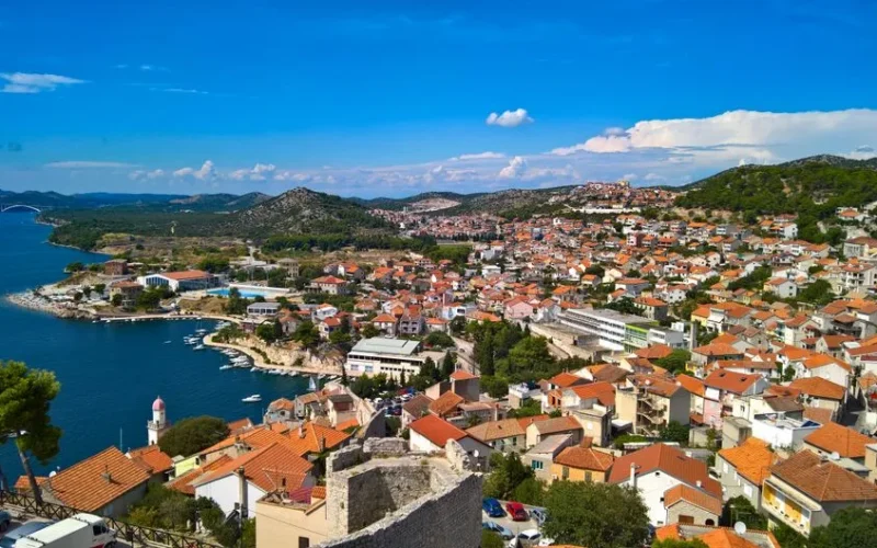 A vibrant view of the coastal town of Sibenik, Croatia, showcasing red roofs and blue Adriatic Sea.
