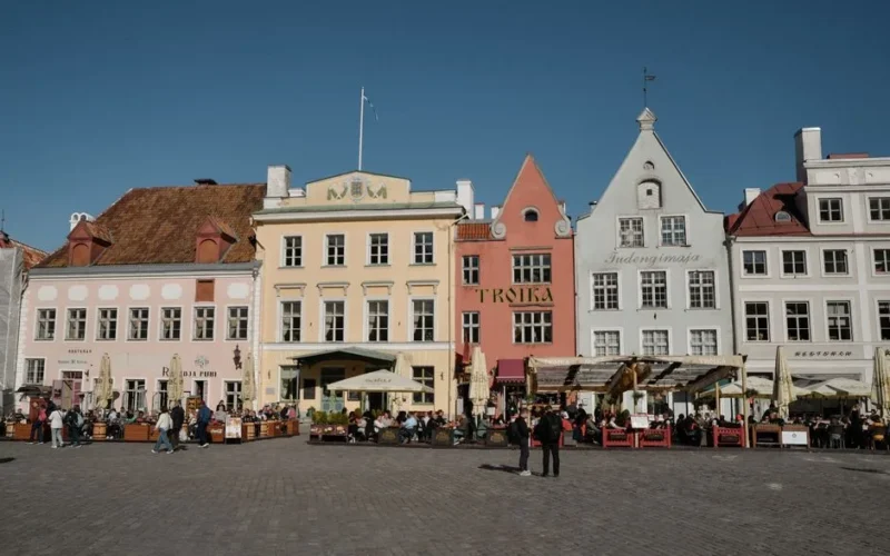 Vibrant facades and outdoor cafes on a sunny day in Tallinn, Estonia, at Town Hall Square.