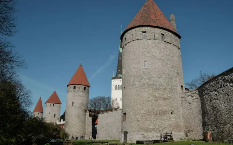 Explore the historic stone towers and red roofs of Tallinn's medieval city wall on a bright spring day.