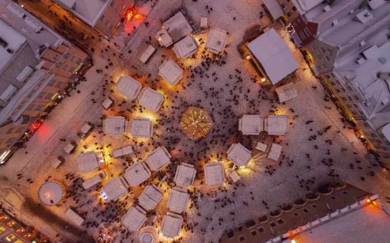 A stunning aerial shot of a festive Christmas market in snowy Tallinn, Estonia during winter.