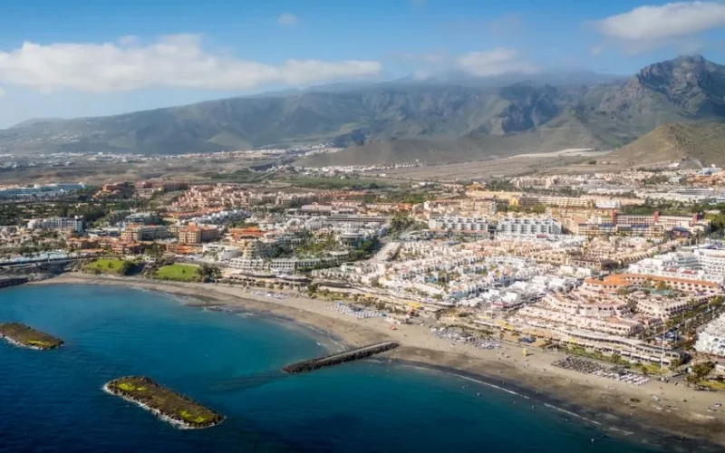 A stunning aerial shot of a coastal town in Tenerife, Canary Islands with mountains in the background.