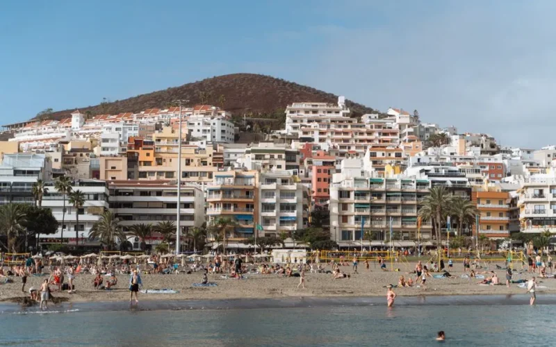 Relaxing beach day with vibrant buildings in Tenerife, Spain.