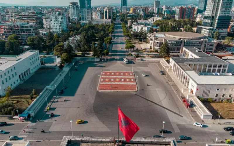 Aerial view of Skanderbeg Square in Tirana, Albania, featuring the iconic Albanian flag and cityscape.