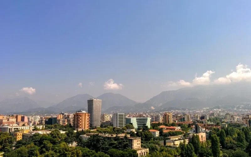 Aerial view of Tirana, Albania's capital, with mountain backdrop and clear skies.