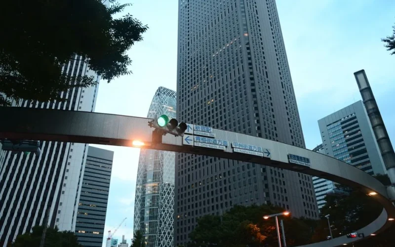 Skyscrapers of Shinjuku, Tokyo captured at dusk with a prominent traffic signal and directional signs.