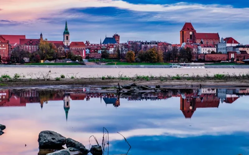 Captivating view of Toruń's medieval architecture reflecting in the Vistula River at dusk.