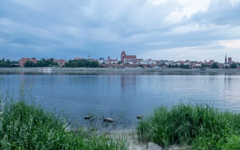 Breathtaking view of Toruń's historic skyline across the calm Vistula River.