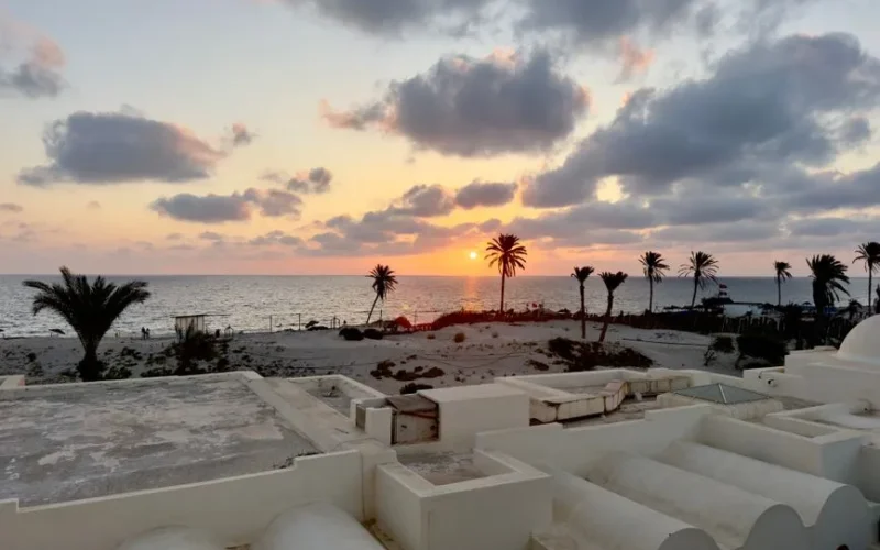 Beautiful sunset view over a beach in Médenine, Tunisia, with palm trees and ocean.
