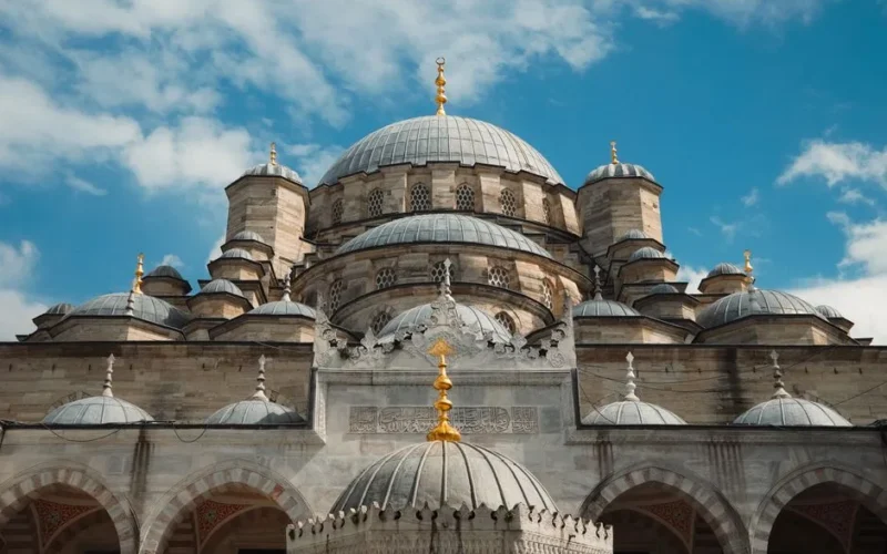 Stunning architectural view of the Yeni Mosque's domes against a clear blue sky in Istanbul.