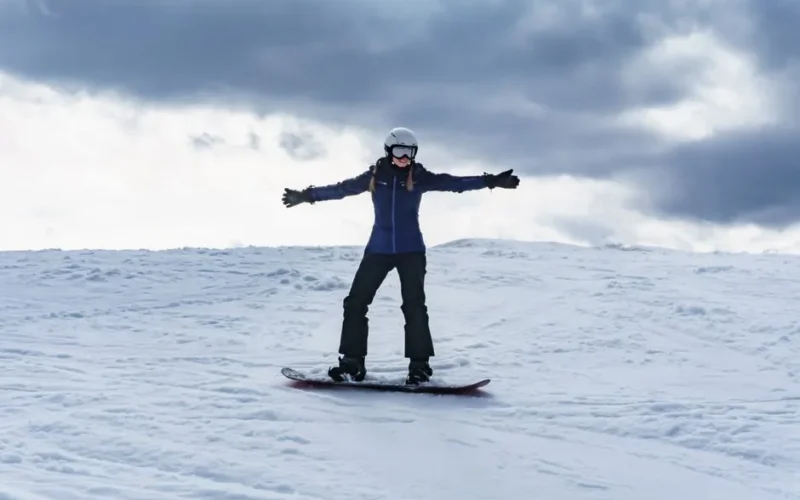 Woman enjoying snowboarding on a winter day in Tylicz, Poland.