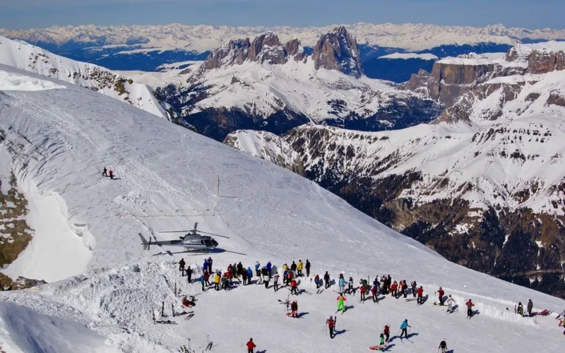 A stunning winter scene of skiers and helicopter on the Dolomites in Italy.