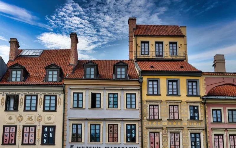 Colorful facades of historic buildings in Warsaw, Poland, under a vibrant blue sky.