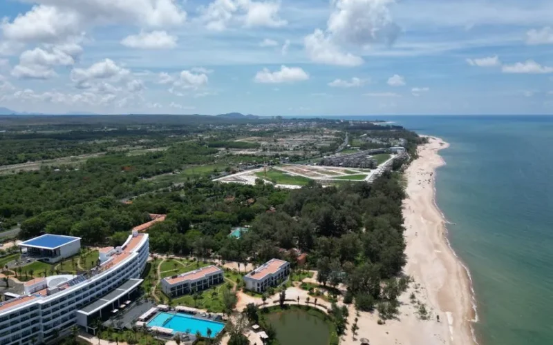 Beautiful aerial view of a luxury beachfront resort in Hồ Tràm, Vietnam, with lush greenery and clear skies.