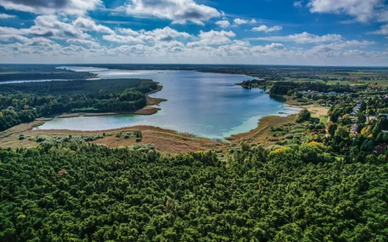 Breathtaking aerial view of a serene lake surrounded by lush forests and cloudy sky.