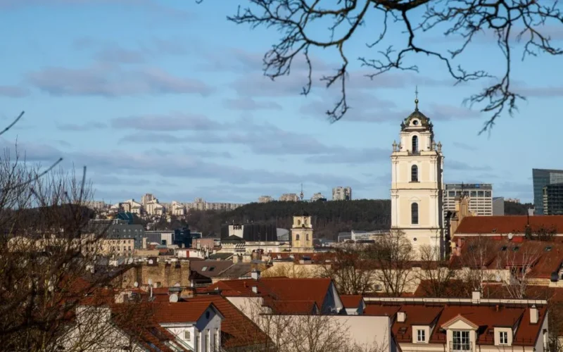 A beautiful view of Vilnius city featuring historic architecture and a prominent church tower under a clear sky.