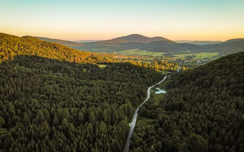Stunning aerial view of Wysowa-Zdrój, showcasing lush forests and rolling hills during a summer sunset.