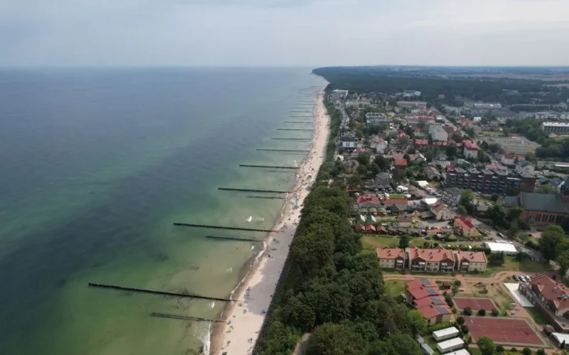 Aerial shot of a coastal town with beach and ocean, showcasing a serene seaside landscape.