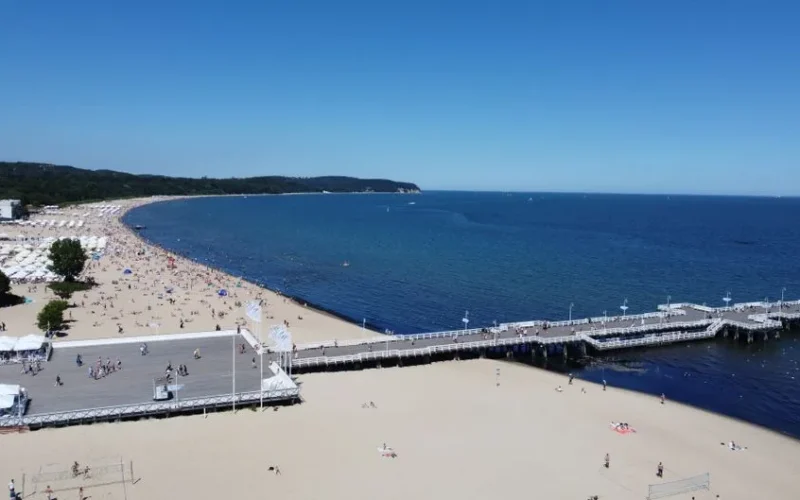 Explore the stunning aerial view of Sopot Pier and beach in Poland under clear blue skies.