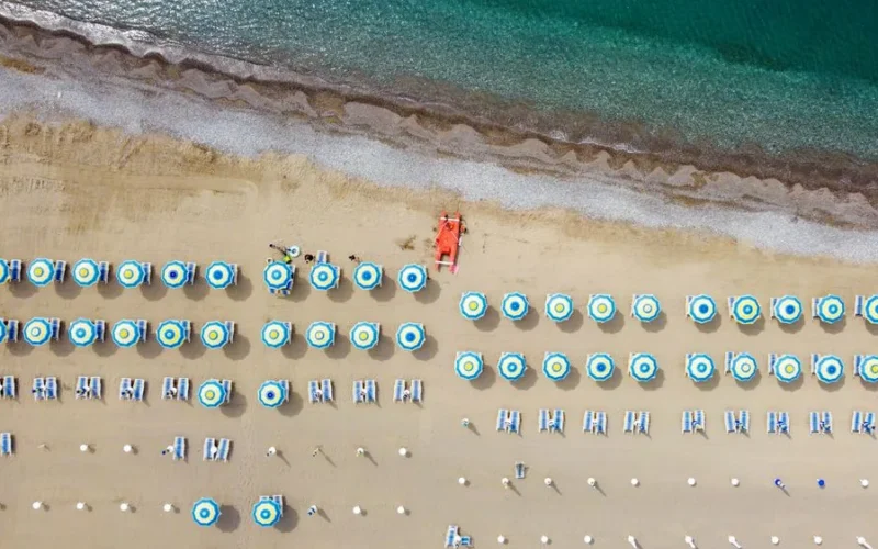 Aerial view of colorful beach umbrellas and loungers on Santa Marina beach, Italy.