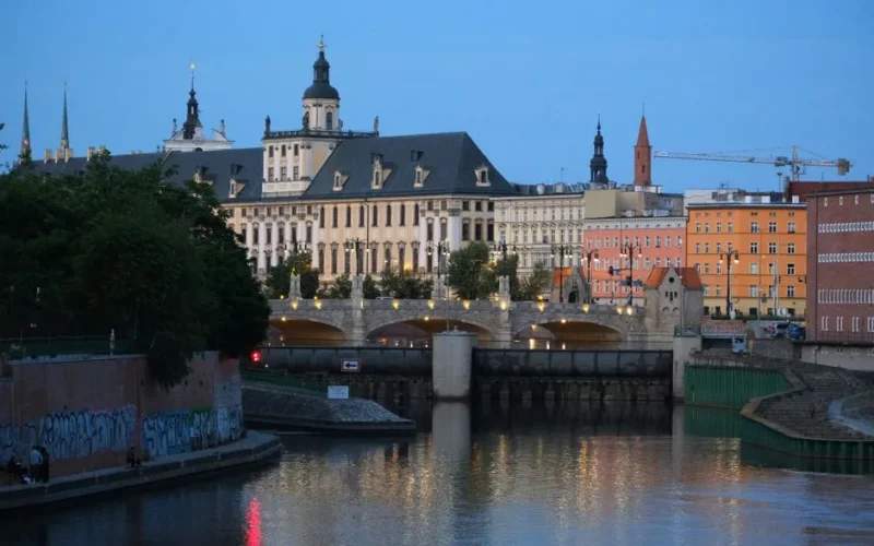 Scenic view of Wroclaw University and colorful buildings by the Oder River during twilight.
