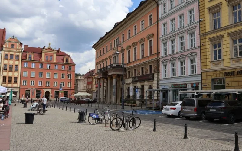 Colorful historic buildings lining Wrocław's bustling main square on a sunny day.