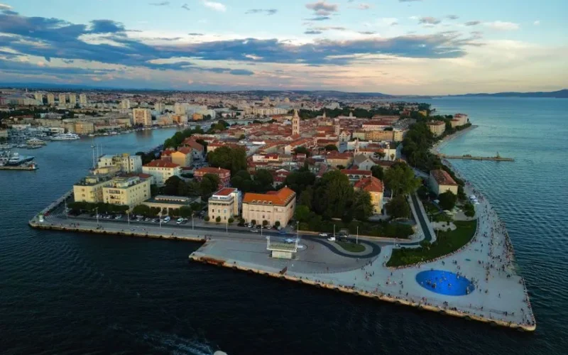 Scenic aerial view of Zadar's peninsula and harbor during sunset with vibrant cityscape and the Adriatic Sea.