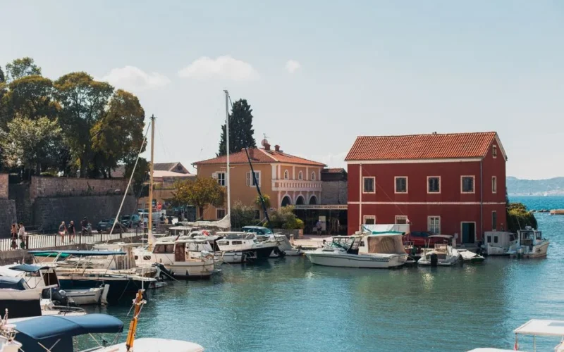 Boats docked in Zadar harbor with vibrant summer backdrop and charming architecture.