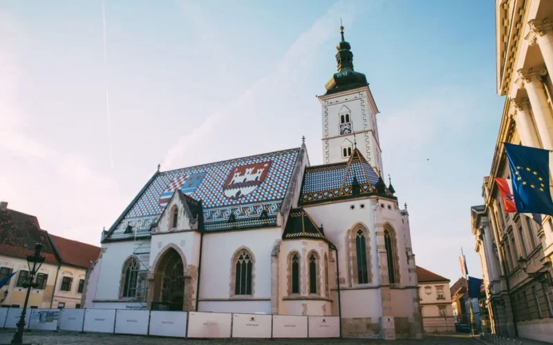 Beautiful view of St. Mark's Church and Town Square in Zagreb, Croatia under a clear blue sky.