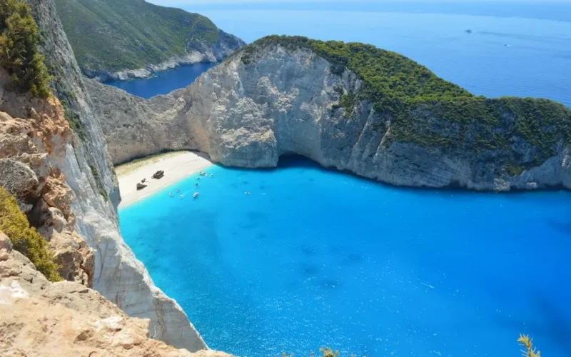 A breathtaking aerial view of Navagio Beach in Zakynthos, showcasing its blue waters and surrounding cliffs.