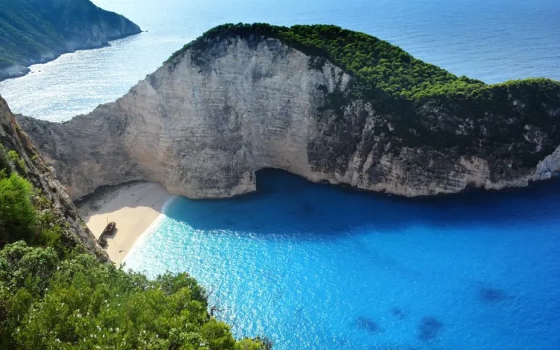 A breathtaking aerial view of Navagio Beach with turquoise waters and lush greenery.