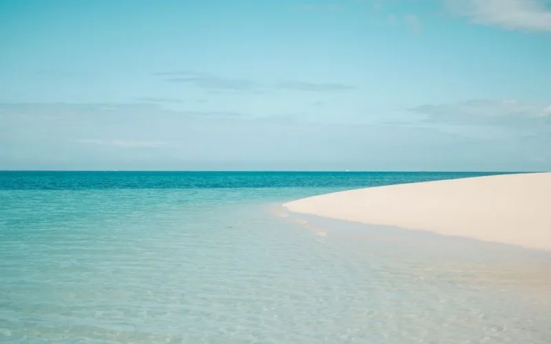 Pristine white sandy beach with clear turquoise ocean in Zanzibar, Tanzania, under a bright summer sky.
