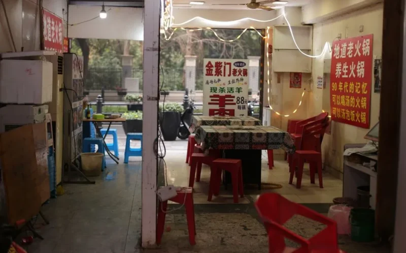Cozy restaurant with red plastic chairs and string lights, creating a vintage Asian dining atmosphere.