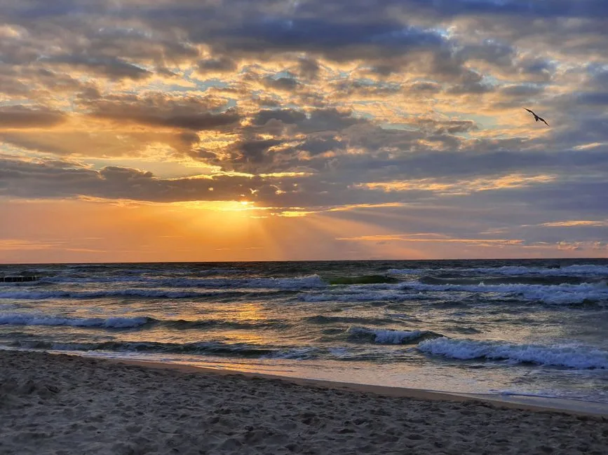 Gorgeous sunset over the ocean at Dziwnówek Beach, Poland with dramatic clouds and waves.